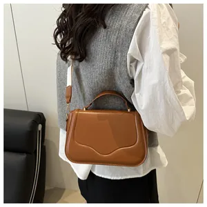 Detail of caramel leather bag with wave stitching and wide woven shoulder strap