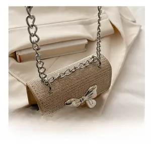 Detail of woven texture handbag with silver bow decoration and metallic chain strap