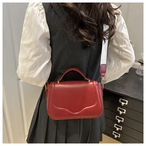 Detail of red leather crossbody bag with wide white fabric strap shown from back view