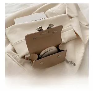 Detail view of the mini beige crossbody bag interior with silver chain and magnetic closure