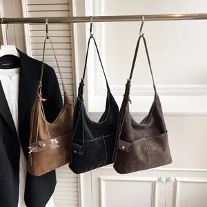 Tre borse tote vintage in pelle opaca nei colori marrone, nero e caffè appese a un'asta