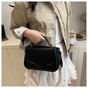 Close-up of black crossbody bag with wave pattern lid and golden hardware details