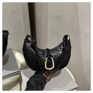 Détail du sac demi-lune noir tressé avec boucle dorée en U et bandoulière à nœud