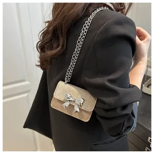 Close-up of beige mini crossbody bag with glitter texture and silver bow detail
