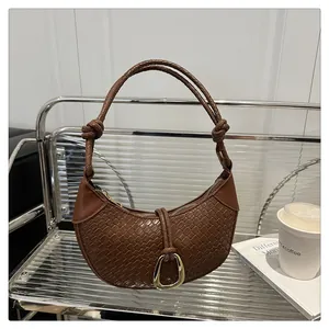 Détail du sac demi-lune tressé marron caramel avec boucle en D et poignée à nœuds
