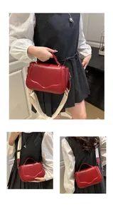 Detail of red saddle bag with wavy flap texture, top handle, and wide fabric shoulder strap