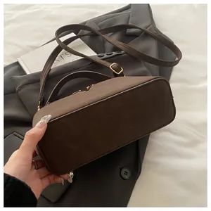 Macro detail of the smooth dark brown suede texture and flat base of the crossbody bag
