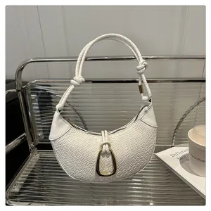 Détail du sac demi-lune blanc en cuir tressé avec nœud décoratif sur le support