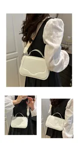 Detail of cream white crossbody bag with wide strap and gold hardware on model
