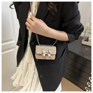 Detailed close-up of beige mini crossbody bag featuring a golden sequin flap and silver bow