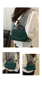 Detail of dark green leather saddle bag featuring wavy stitching and wide fabric strap