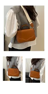 Detail of brown saddle bag with unique wavy stitching and white woven shoulder strap