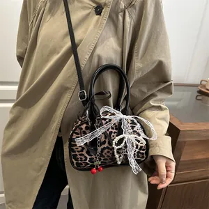 Leopard print crossbody bag with lace bow and cherry charm accessory on a model