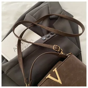Detail view of dark coffee leather crossbody bag with golden V hardware decoration