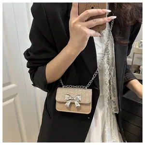 Close-up of mini chain bag featuring silver sequin flap and metallic bow decoration