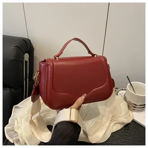 Detail of dark red crossbody bag with wide woven strap and matte leather texture