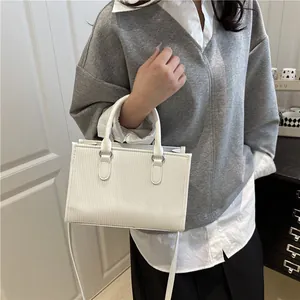 Detailed view of a white rectangular handbag with vertical texture and silver hardware