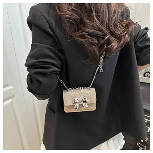 Detail of apricot sequin crossbody bag with silver metal bow and delicate chain strap