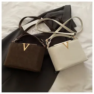 Detail view of structured trapezoid handbags in dark brown and off-white with golden V clasp