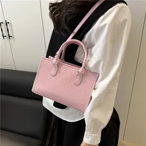 Detail of light pink pleated cylindrical handbag with top handles and shoulder strap