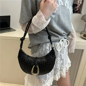 Sac hobo tissé noir avec boucle dorée et bandoulière nouée en scène de vie moderne