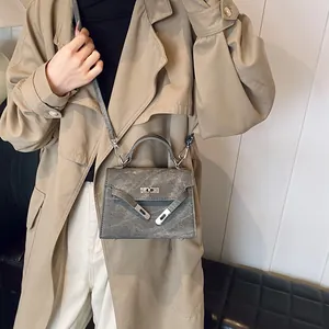 Borsa a mano a trapezio grigia testurizzata con dettagli argento indossata