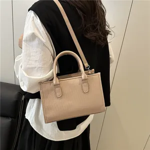 Detail view of the vertical ribbed texture on a beige cylindrical shoulder bag worn by model