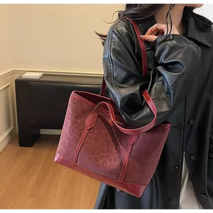 Detail of burgundy leopard print tote bag featuring matte suede and smooth leather textures