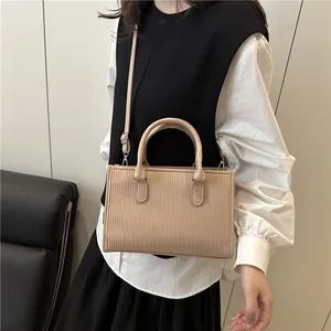 Minimalist beige cylinder barrel handbag with vertical embossed texture and top handles