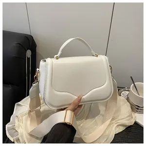 Close-up of white crossbody bag featuring embossed wave texture and wide fabric strap