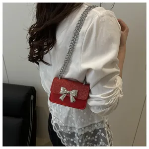 Detailed view of red mini shoulder bag with glitter flap and silver bow chain strap