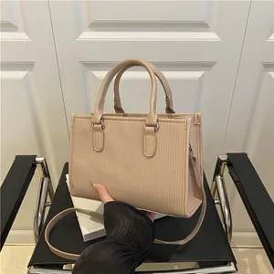 Close-up of beige handbag with vertical ribbed texture and dual circular handles