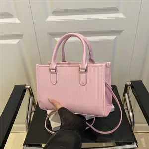 Detailed view of pink textured cylindrical tote with vertical stripes and metallic D-rings
