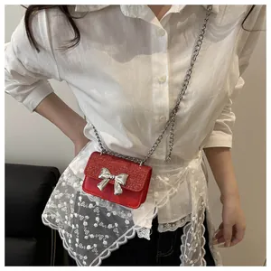 Close-up of mini red sequin crossbody bag with silver bow on white lace blouse