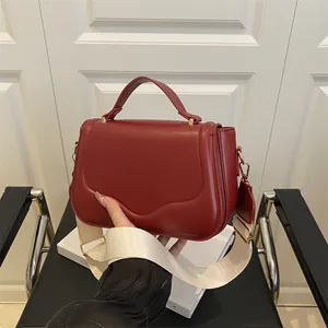 Fashionable dark red crossbody bag with wide woven strap and golden hardware