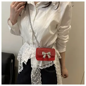 Detail of red glitter mini bag with silver bow buckle and elegant metal chain strap