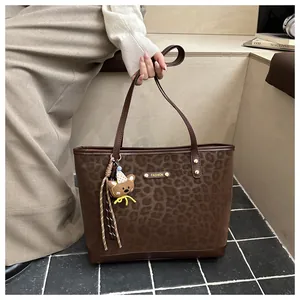 Detail of leopard print tote bag with soft suede texture and a cute bear charm
