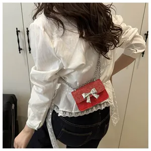 Close-up of a red glitter mini bag with silver bow buckle and chain strap on a model