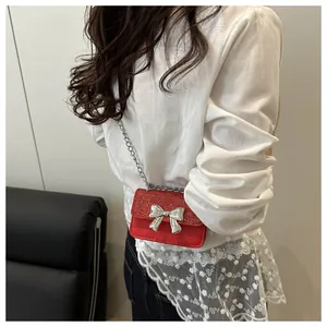 Macro detail of red glitter mini bag with silver bow accent and metal chain strap