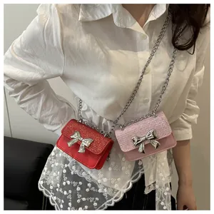 Close-up of mini crossbody bags in red and pink featuring a silver metal bow buckle
