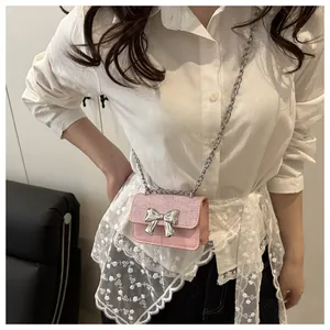 Detail of pink mini crossbody bag featuring a silver metal bow and sequin texture