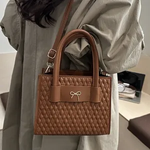 Chic brown quilted crossbody bag with a gold bow buckle, shown in a modern urban lifestyle setting