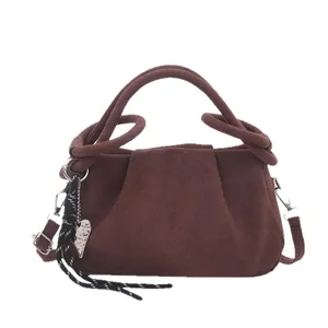 Brown frosted trapezoid handbag with knotted handle and heart charm on white background
