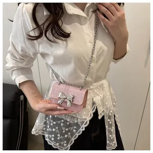 Detail showing pink tweed mini bag with silver bow accent and chain strap on a model