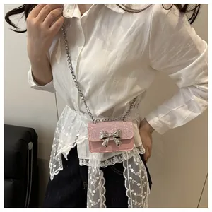 Detail of pink glitter mini bag with silver bow ornament and metallic chain strap