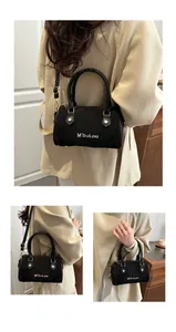 Détails du sac Boston noir mat avec lettrage blanc et rivets métalliques dorés