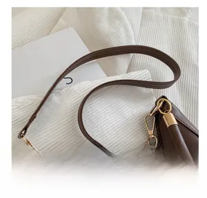 Detailed close-up of dark brown leather handbag with elegant gold metal ring connectors