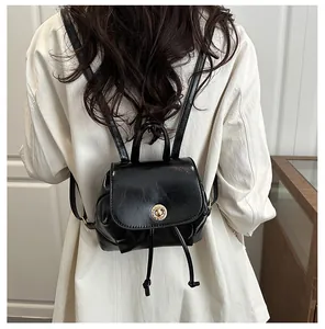 Détail d'un mini sac à dos noir avec fermoir doré et cordon de serrage porté par un mannequin