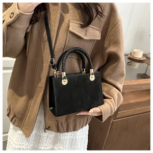 Detail of vintage black crossbody bag featuring embossed clover patterns and woven handle