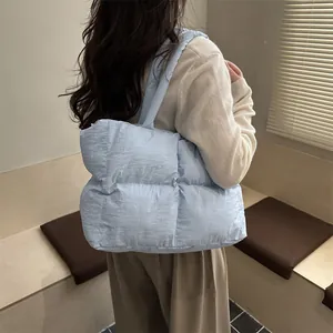 Quilted light blue puffy tote bag for women showing a stylish shoulder carry on a model